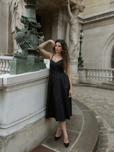 A woman wears a black midi dress